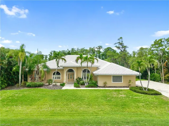 Front elevation featuring a new tile roof, paver driveway, mature tropical landscaping, and oversized garage, ideally situated on one of Fiddlesticks Country Club's most private golf course homesites.