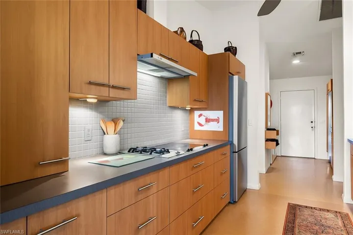 Kitchen with modern cabinets, tasteful backsplash, under cabinet range hood, and freestanding refrigerator