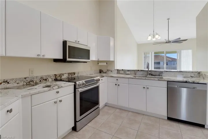 Kitchen featuring sink, ceiling fan, appliances with stainless steel finishes, white cabinetry, and light tile patterned flooring