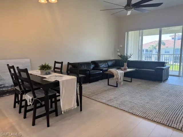 Dining room featuring light wood-style floors, a ceiling fan, and a high ceiling
