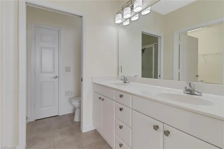Bathroom featuring walk in shower, vanity, toilet, and tile patterned flooring