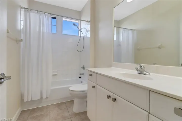 Full bathroom featuring tile patterned flooring, vanity, shower / tub combo with curtain, and toilet