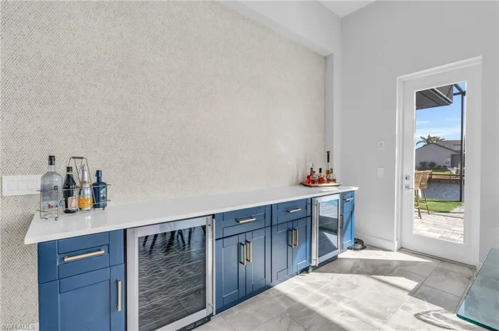 Bar featuring wine cooler, blue cabinets, and plenty of natural light