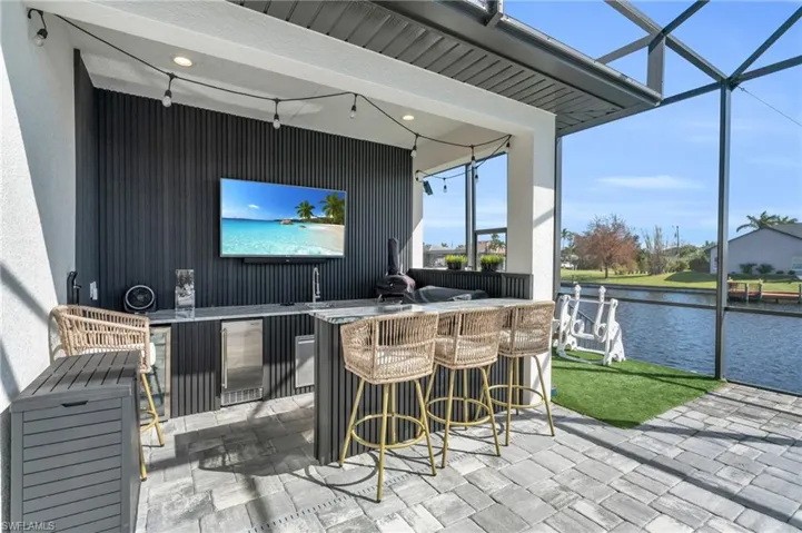 View of patio featuring a bar and glass enclosure