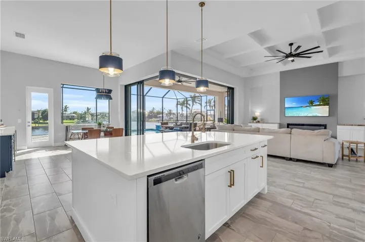 Kitchen featuring sink, coffered ceiling, pendant lighting, stainless steel dishwasher, and a center island with sink