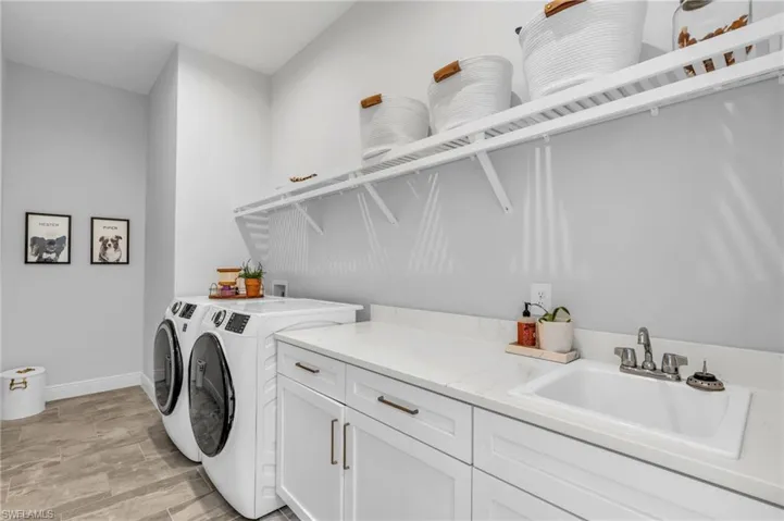 Laundry area with sink, washing machine and clothes dryer, and cabinets
