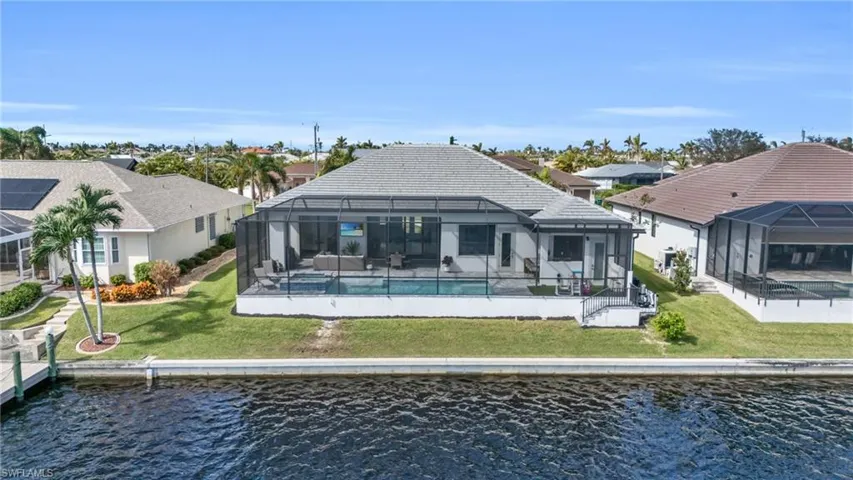 Rear view of property featuring a patio area, a water view, a lawn, and a lanai