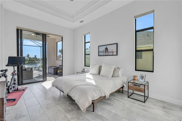 Bedroom with multiple windows, access to exterior, a water view, and crown molding