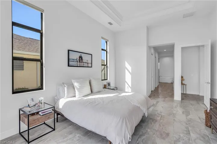 Bedroom featuring multiple windows, a raised ceiling, and crown molding