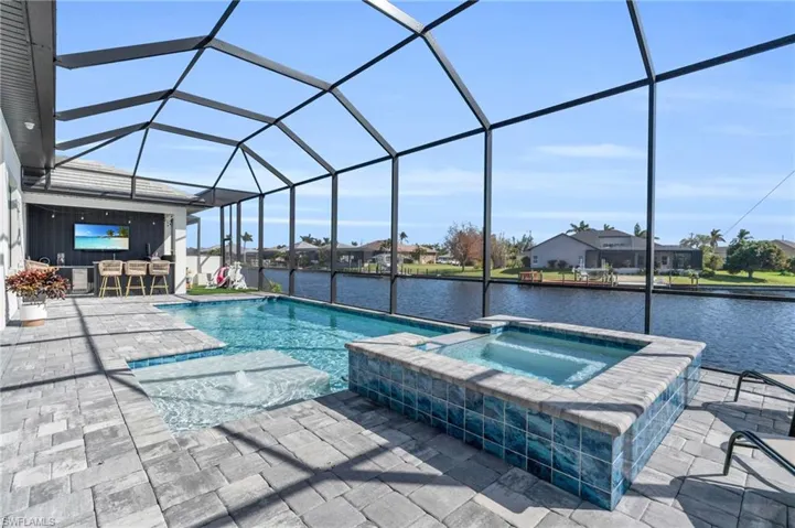 View of pool featuring a patio area, a lanai, an in ground hot tub, and a water view