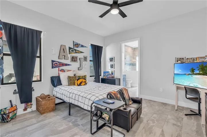 Bedroom with ensuite bath, multiple windows, and ceiling fan
