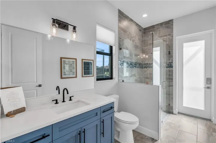 Bathroom featuring a shower with door, vanity, and toilet
