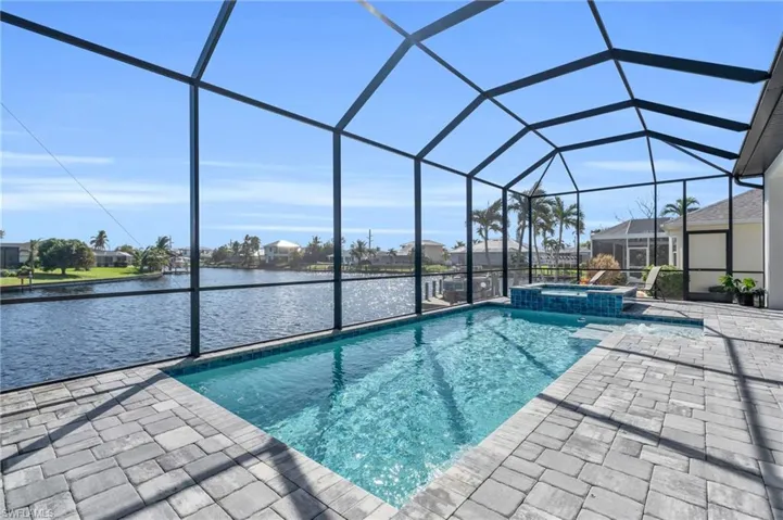 View of swimming pool with a patio area, an in ground hot tub, a water view, and a lanai