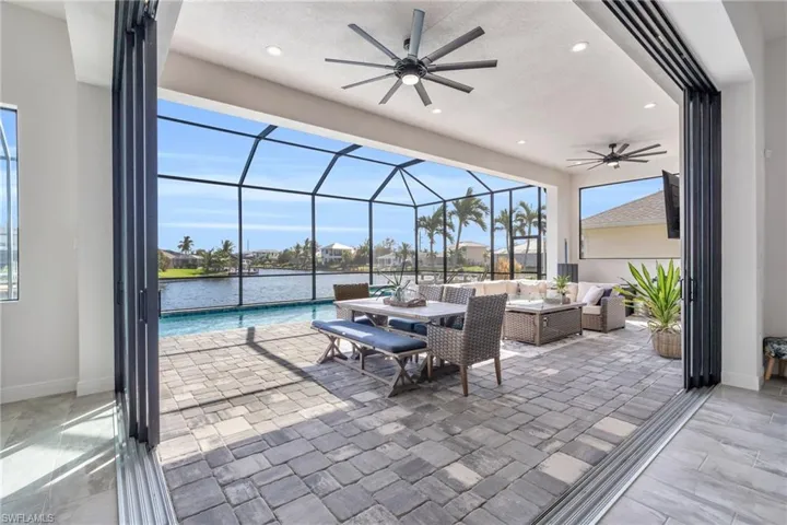 View of patio featuring a lanai, an outdoor living space, a water view, and ceiling fan