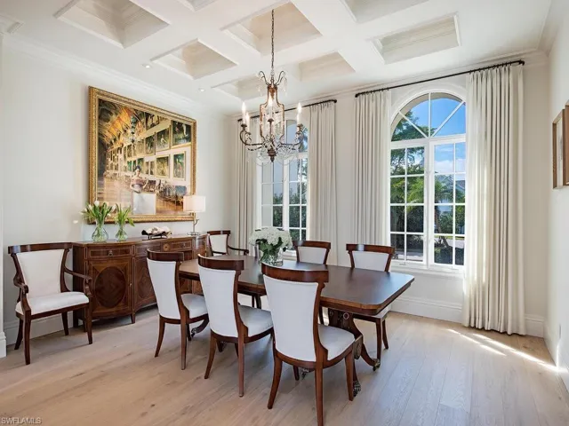 Dining room with a chandelier, crown molding, light wood-style flooring, coffered ceiling, and beam ceiling