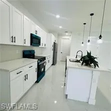 Kitchen featuring white cabinetry, electric stove, an island with sink, and light countertops