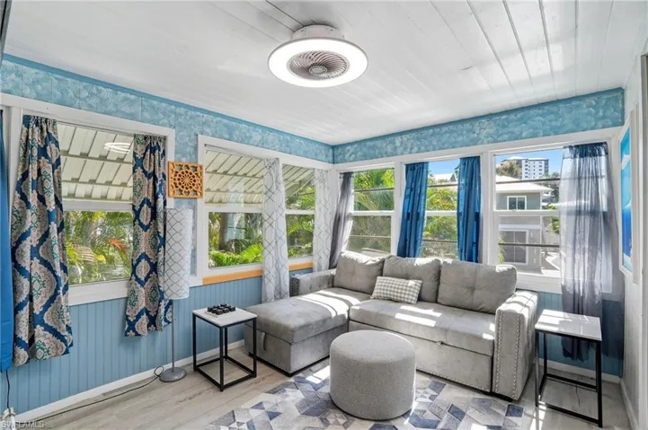 Sunroom / solarium featuring wood finished floors, wallpapered walls, and wood ceiling - Virtually Edited Image