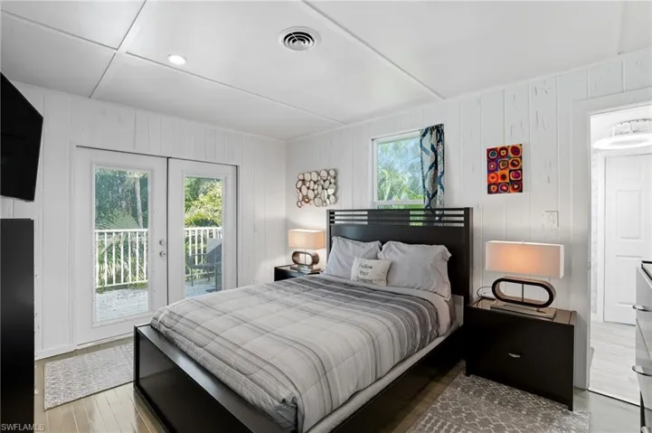 Bedroom with access to exterior, wooden walls, wood finished floors, and recessed lighting - Virtually Edited Image