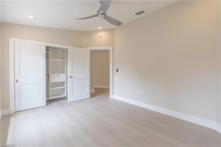 Unfurnished guest bedroom 1 with a closet, lofted ceiling, ceiling fan, and light wood-type flooring