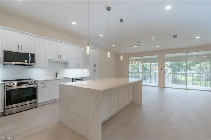 Large center island with waterfall quartz and dual sided cabinet storage, ample storage including pantry cabinet