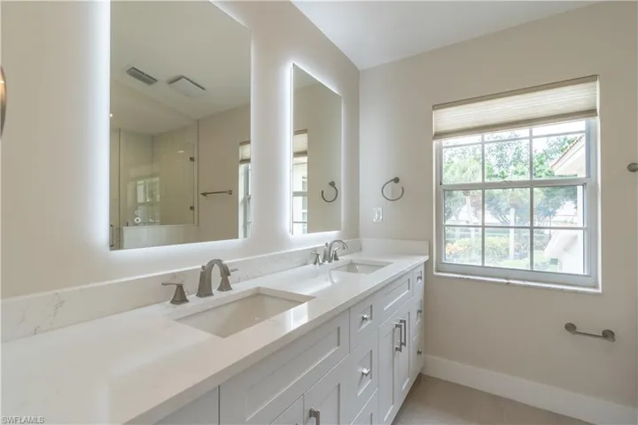 Bathroom featuring dual vanity, lighted mirrors