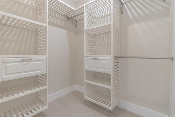 Primary suite walk in closet with custom shelving