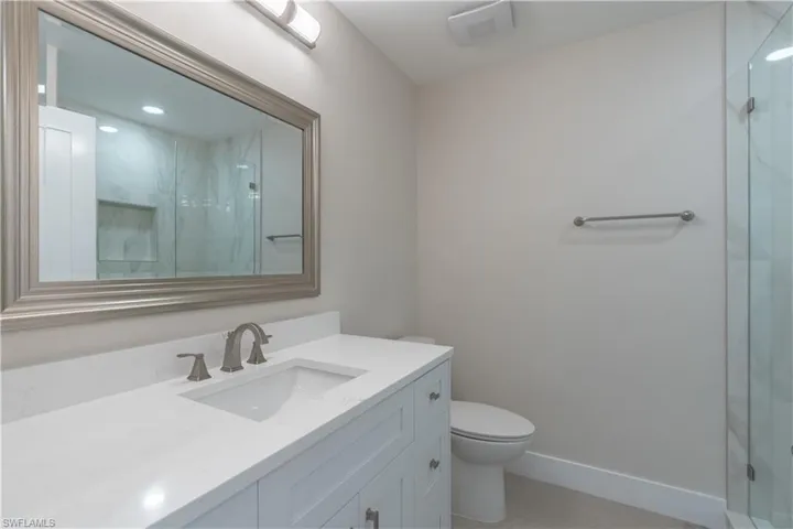 Bathroom featuring vanity, walk in shower, and toilet