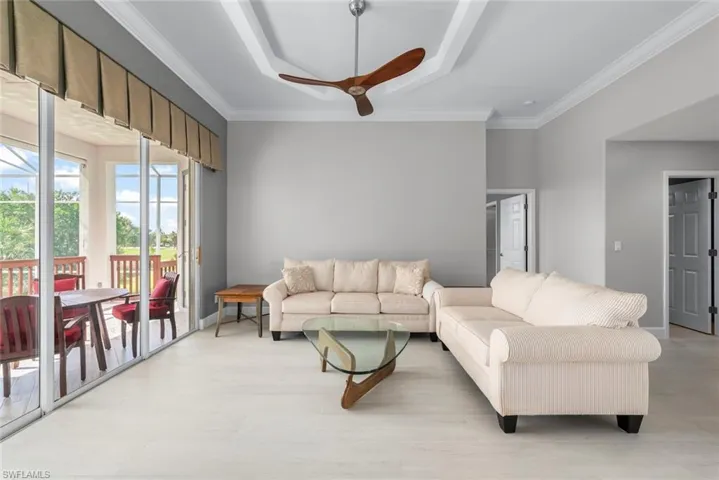 Spacious interior featuring light wood-finish flooring, a tray ceiling with a ceiling fan, and crown molding