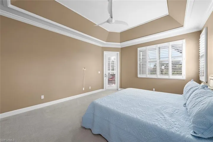 Spacious room featuring a tray ceiling with crown molding, light beige wall color, and light-colored carpeting