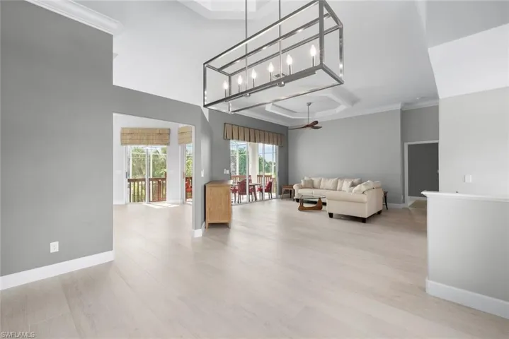 Expansive room featuring light wood-finish flooring, high vaulted ceilings, and a contemporary rectangular chandelier
