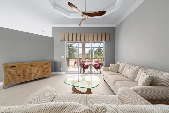 Living space featuring light wood-finish flooring and a tray ceiling with crown molding