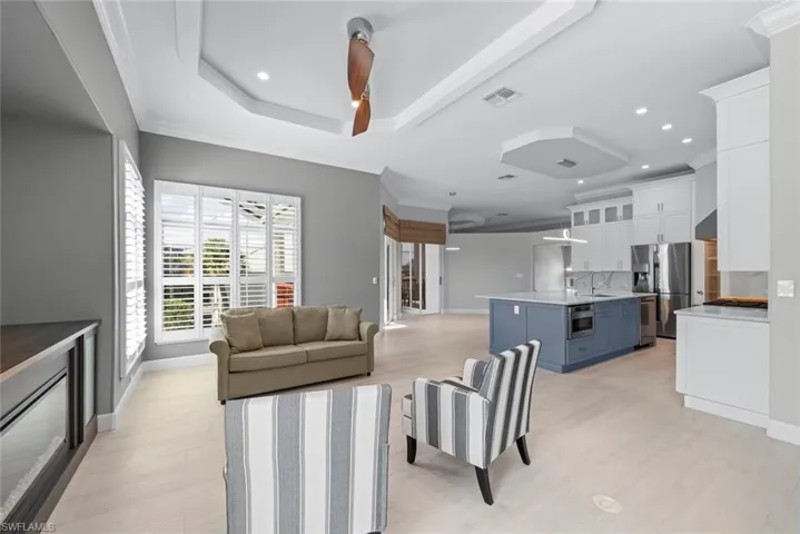 Open-concept living space featuring light wood-finish flooring, recessed lighting, and tray ceilings