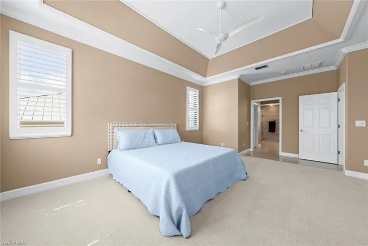 Spacious room with a tray ceiling, ceiling fan, and carpeted flooring
