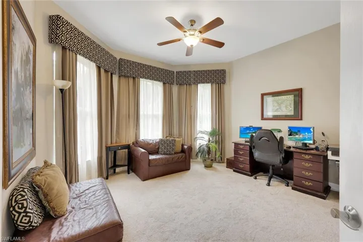 Office with light carpet and a ceiling fan