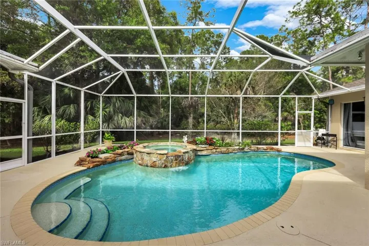 Relaxing pool / spa with a sunroom, glass enclosure, and a patio