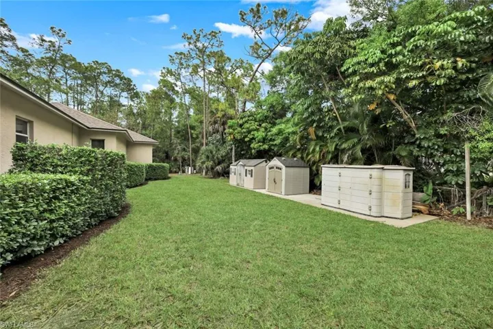 View of green lawn featuring a storage shed and view of wooded area