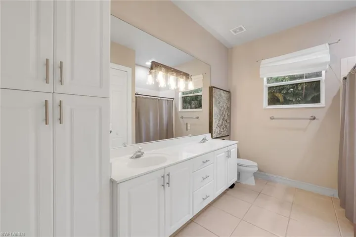 Full bathroom with a shower with curtain, double vanity, and light tile patterned floors