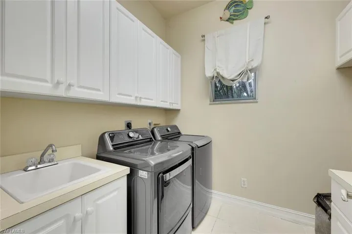 Laundry area featuring cabinet space, separate washer and dryer, and light tile patterned floors