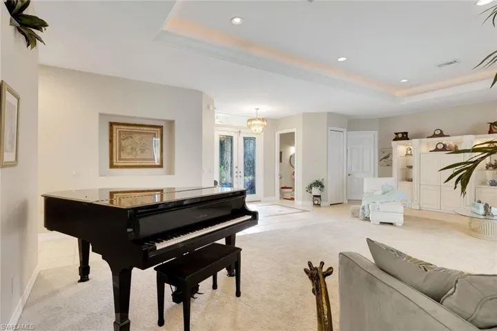 Sitting room featuring french doors, carpet flooring, a tray ceiling, hanging lights, and tile patterned floors