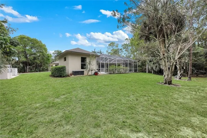 Back of property featuring glass enclosure, a sunroom, a lawn, and stucco siding