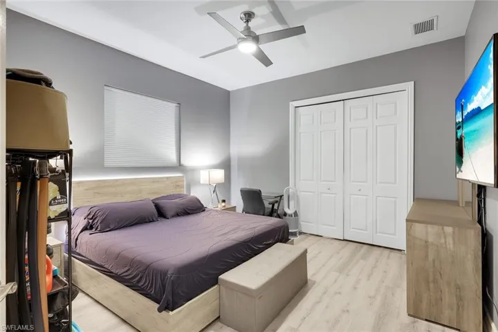 Bedroom with light wood finished floors, ceiling fan, and a closet