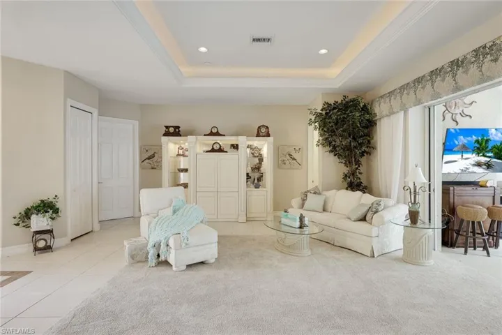 Tiled living room with a tray ceiling and recessed lighting