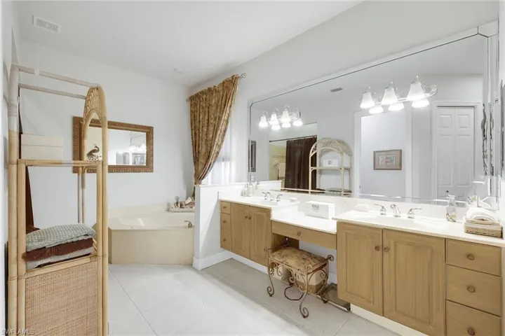 Bathroom featuring double vanity, light tile patterned floors, and a garden tub
