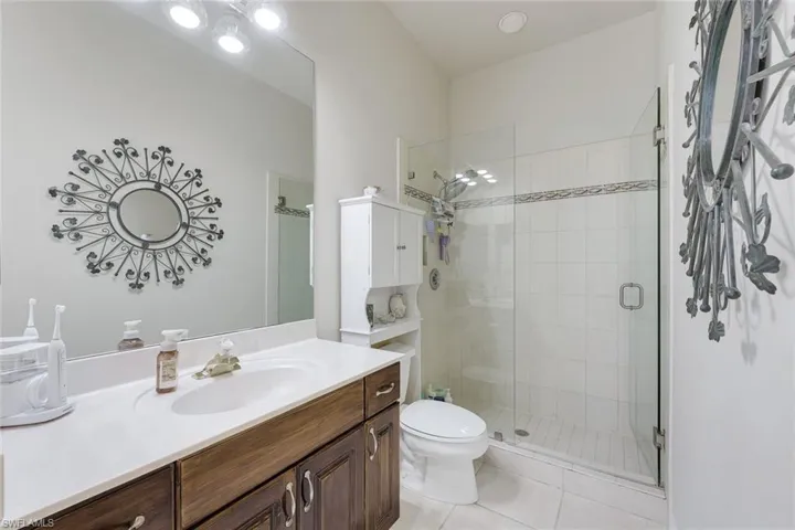 Full bath with a stall shower, vanity, and light tile patterned floors