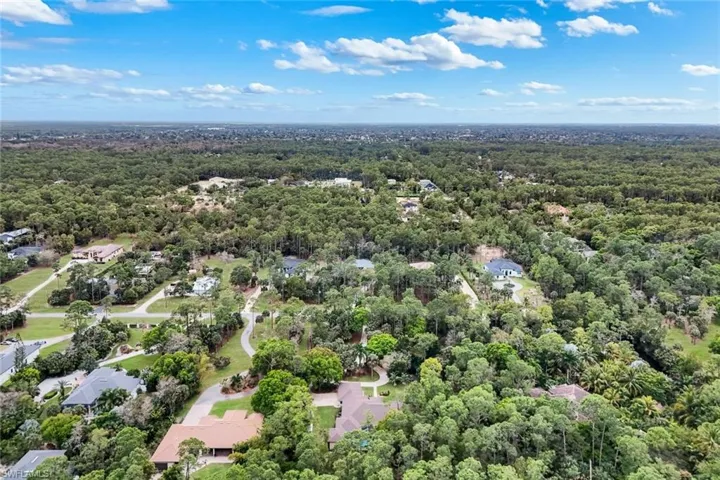 Aerial view of property's location featuring a forest and nearby suburban area