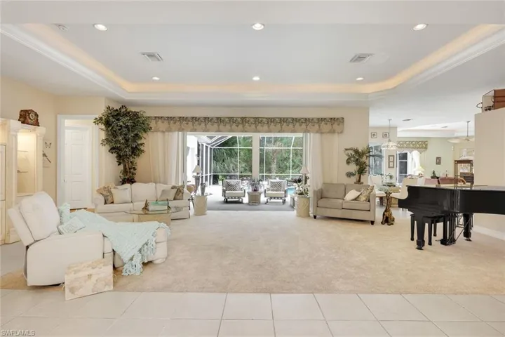 Living room featuring a raised ceiling, light carpet, and recessed lighting