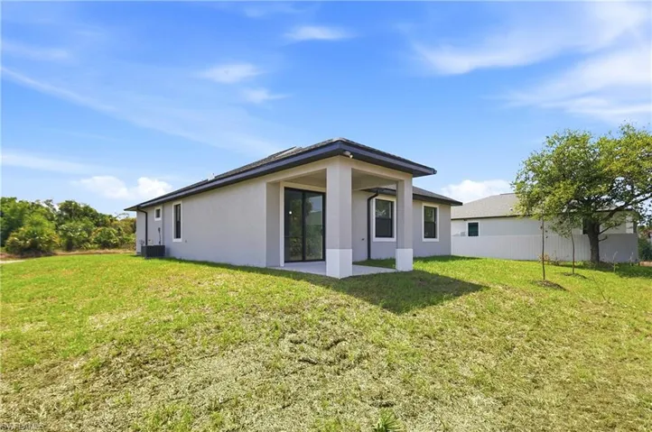 Back of house featuring a patio area, a yard, and stucco siding