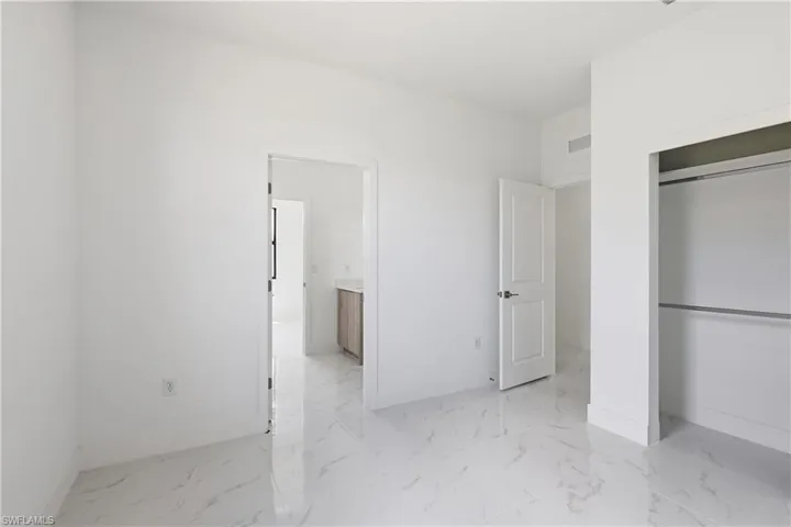 Bedroom with a closet, light marble finish flooring, and ensuite bathroom