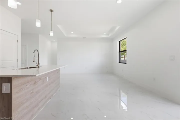living room featuring light marble finish floors, a raised ceiling, and recessed lighting