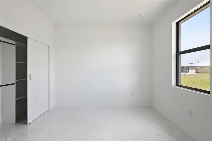 Bedroom featuring light marble finish flooring and a closet